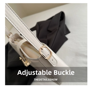 Detail view of adjustable gold buckle and smooth white leather strap on shoulder bag