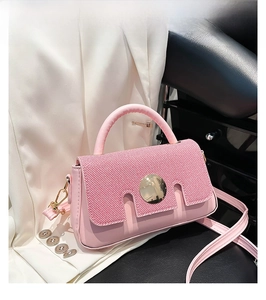 Detail of pink crossbody bag with diagonal woven pattern and large round gold metal buckle