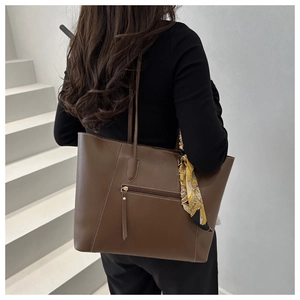 Detail of dark brown tote bag featuring white contrast stitching and decorative silk scarf