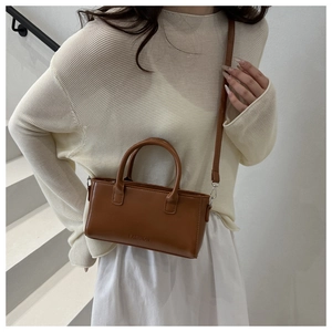 Sac bandoulière carré en cuir PU marron porté par un mannequin en milieu urbain