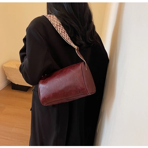 Details der weinroten Zylindertasche mit Vintage-Kunstleder und geometrischem Jacquard-Gurt