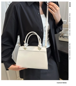 Detail view of the knotted ring handle and golden hardware on the white crossbody bag