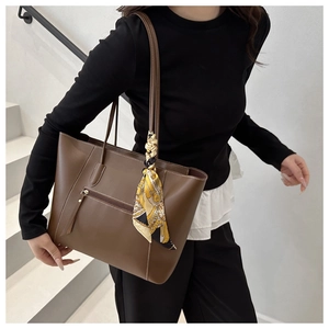 Detail view of brown pebbled leather tote bag with silk scarf and front zipper pocket