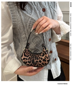 Détail de la texture léopard et des finitions dorées du sac à main en demi-lune