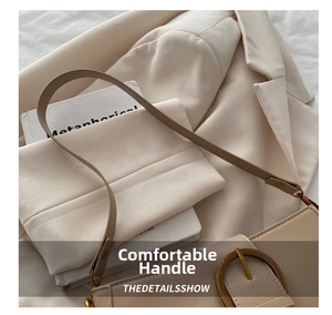 Détail du sac sous le bras en cuir beige avec grande boucle en bronze et texture douce