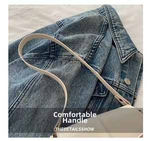 Detail of white glossy leather handbag with vertical stitching on denim jacket