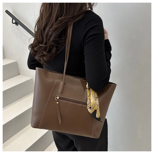 Detail of a large brown tote bag with white stitching and printed silk scarf accessory