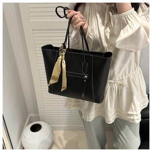 Detail of black tote bag with white contrast stitching and decorative silk scarf on handle