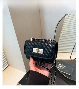 Detail of black quilted mini bag with gold twist lock and chain strap for crossbody use