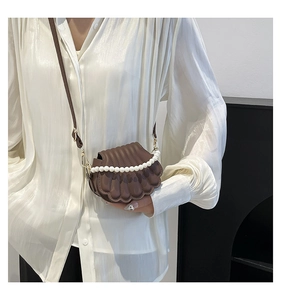 Detailed view of the shell-shaped textured brown leather bag with elegant pearl handle