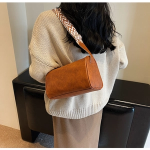 Braune Zylindertasche mit gewebtem Gurt in der Rückansicht am Model präsentiert