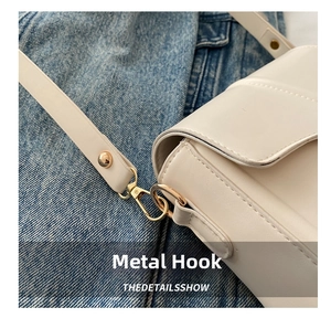 Detail view of cream saddle bag featuring polished gold hardware and fine stitching