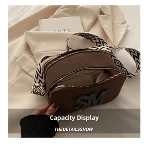 Detail view of brown camera bag with dual zippers and geometric retro wide strap