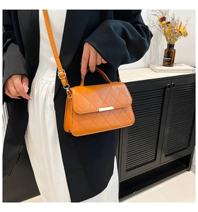 Close-up of orange quilted crossbody bag showing gold lock and stitch details