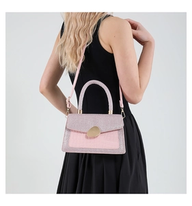 Detail der rosa Krokoprägung-Tasche mit Glitzerklappe und goldener Schnalle am Modell