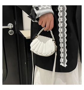 Detail of white shell-shaped handbag with pearl handle and refined stitching texture
