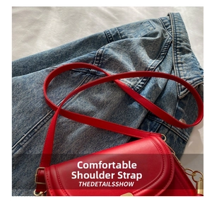 Close-up of vibrant red leather saddle bag featuring gold metal hardware and wide strap