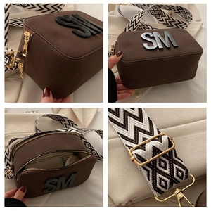 Detail view of coffee brown crossbody camera bag with wide strap and gold hardware