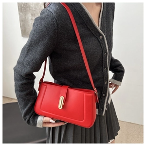 Détail d'un sac à bandoulière rouge vintage avec une boucle ovale en métal doré