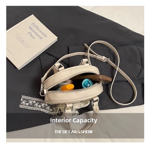Internal capacity of cream oval handbag showing phone, lipstick and small cosmetics inside