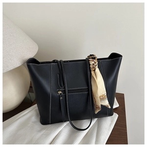 Close-up of black tote bag with white contrast stitching and elegant scarf detail