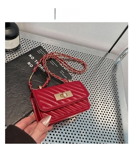 Detail of red quilted mini crossbody bag featuring golden twist lock and leather chain strap