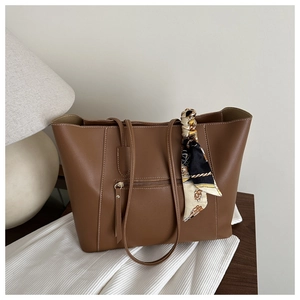 Detailed view of caramel leather tote bag featuring a decorative scarf and zip pocket