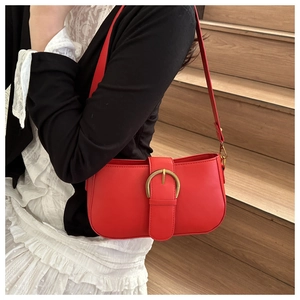 Gros plan d'un sac porté épaule rouge vintage avec une grande boucle de ceinture dorée