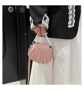 Detail of pink shell-shaped crossbody bag with pearl handle and wave texture