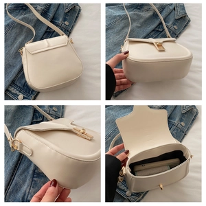 Detail view of cream saddle bag featuring a polished gold twist lock and interior storage