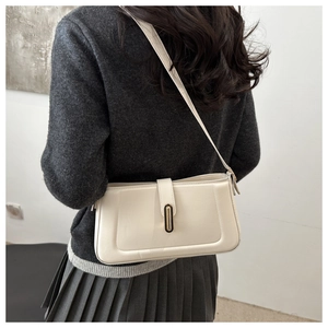Detailed close-up of a cream white leather underarm bag with elegant metal buckle detail