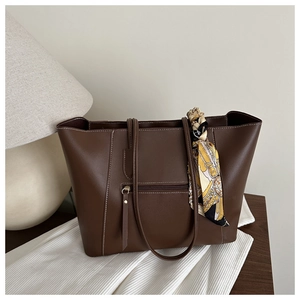 Detail of dark brown leather tote bag with white stitching and floral scarf accessory