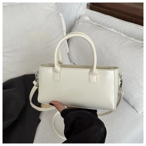 Detailed view of cream square handbag featuring dual handles and embossed fashion text
