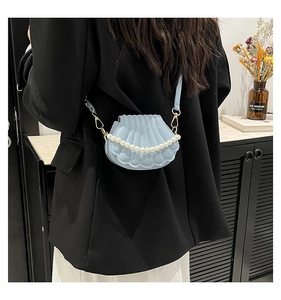 Detail of light blue shell crossbody bag with pearl handle and 3D textured pleats