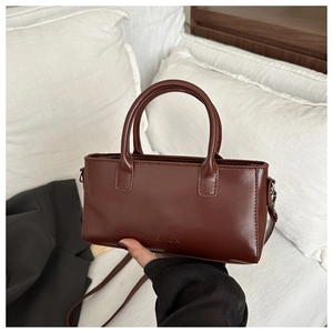 Detail of dark brown faux leather tote bag showing smooth texture and fashion lettering