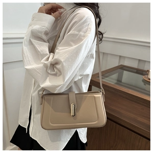 Détail du sac à bandoulière beige minimaliste avec texture lisse et boucle dorée