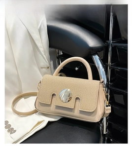 Detail of khaki crossbody bag featuring woven texture flap and round silver metal buckle