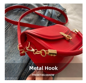 Detail of red leather handbag with gold metal clasp and D-ring on denim jacket