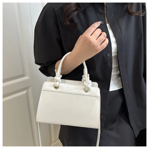 Close-up of a white leather handbag with a woven knot handle and golden hardware details