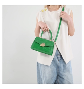 Detail of emerald green crocodile embossed mini bag with glitter finish and gold hardware