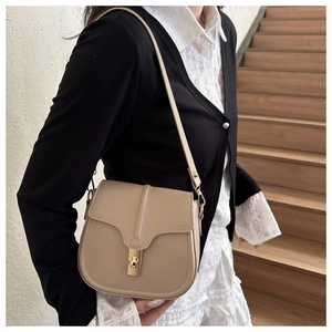 Detail of a beige saddle bag with a golden metallic lock and adjustable leather strap