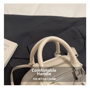 Detailed top view of off-white embossed Boston bag with silver zipper and round handles
