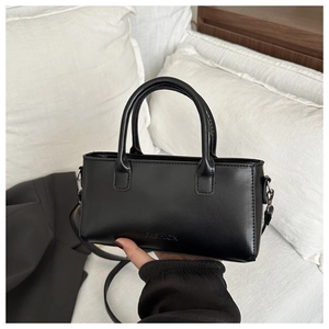 Detail of black leather square handbag featuring FASHION embossing and versatile strap