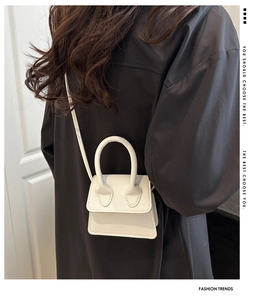 Micro white handbag styled on a black coat with adjustable shoulder strap and top handle