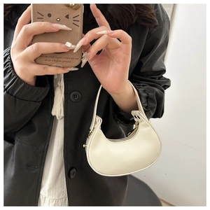 Gros plan du sac à main croissant blanc montrant sa taille compacte et son design épuré