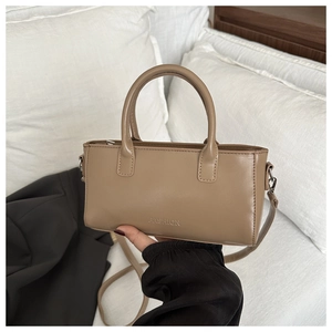 Close-up of khaki faux leather handbag with circular handles and FASHION engraving