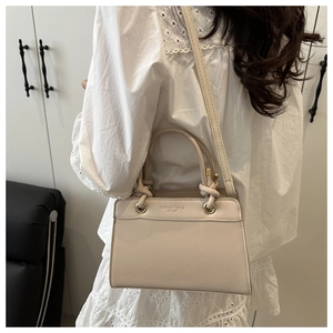 Detail of cream leather handbag with knot handle and Fashion Trend text on model