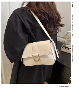Details der cremefarbenen Krokodil-Schultertasche mit goldener D-Schnalle am Model