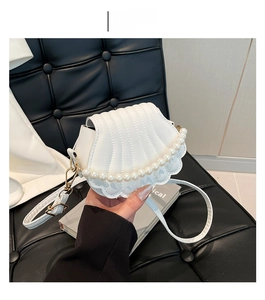 Close-up of white shell crossbody bag with pleated texture and pearl trim details