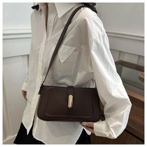 Gros plan d'un sac à bandoulière marron foncé avec boucle capsule dorée et surpiqûres en U